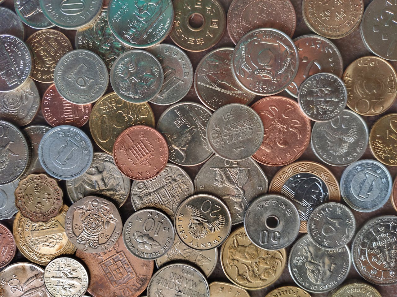 Diverse collection of world coins in a flat lay arrangement, showcasing different currencies and designs.